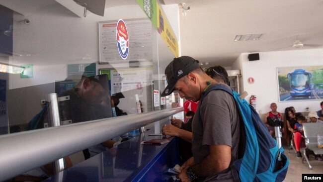 Un migrante que salió de una caravana, luego de recibir sus documentos para cruzar el país, compra un boleto de autobús, en una estación de autobuses en Huixtla, México 10 de junio de 2022. REUTERS/Quetzalli Nicte-Ha.
